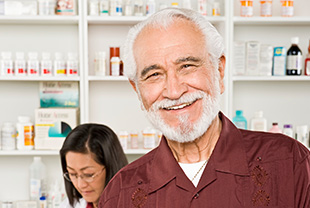 Smiling man at pharmacy with pharmacist standing behind him.