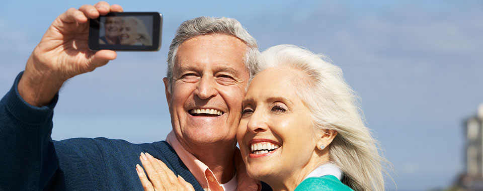 Smiling elderly couple smiling taking a selfie with a smartphone